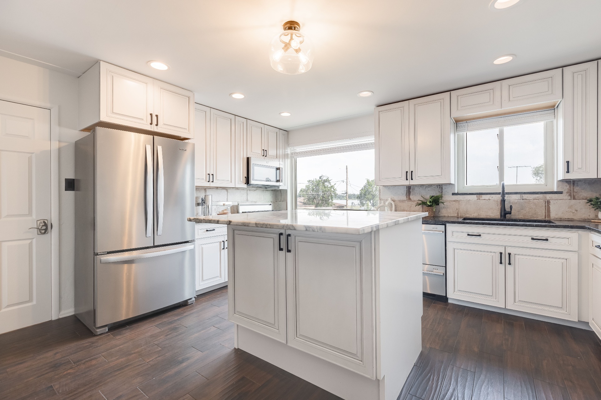 Chef's kitchen with a large quartz island, pendant lighting, and custom cabinetry